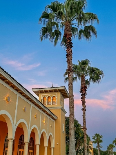 An exterior shot of Rosen Shingle Creek at sunset with a pink and blue sky and tall palm trees. 