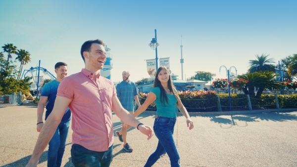 Three men and a woman smiling and walking along a pathway at SeaWorld Orlando. 