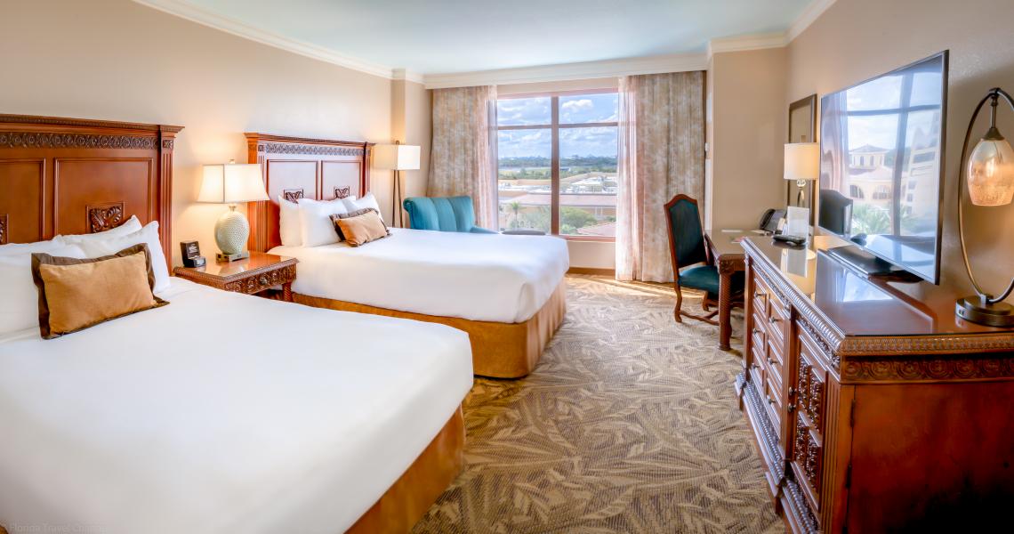A room with two queen beds, a large window, and wooden bed frames at Rosen Shingle Creek, perfect for a family. 