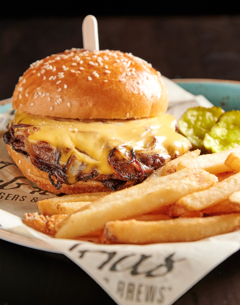 The Restaurants at Rosen Shingle Creek: A Different Dinner Every Night 11 A juicy burger and a side of fries in a basket with paper branded with Tobias Burgers & Brew on it.