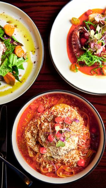 The Restaurants at Rosen Shingle Creek: A Different Dinner Every Night 8 An overhead shot of three plates, one with octopus, another with a salad, and another with pork chop and red sauce at Cala Bella.