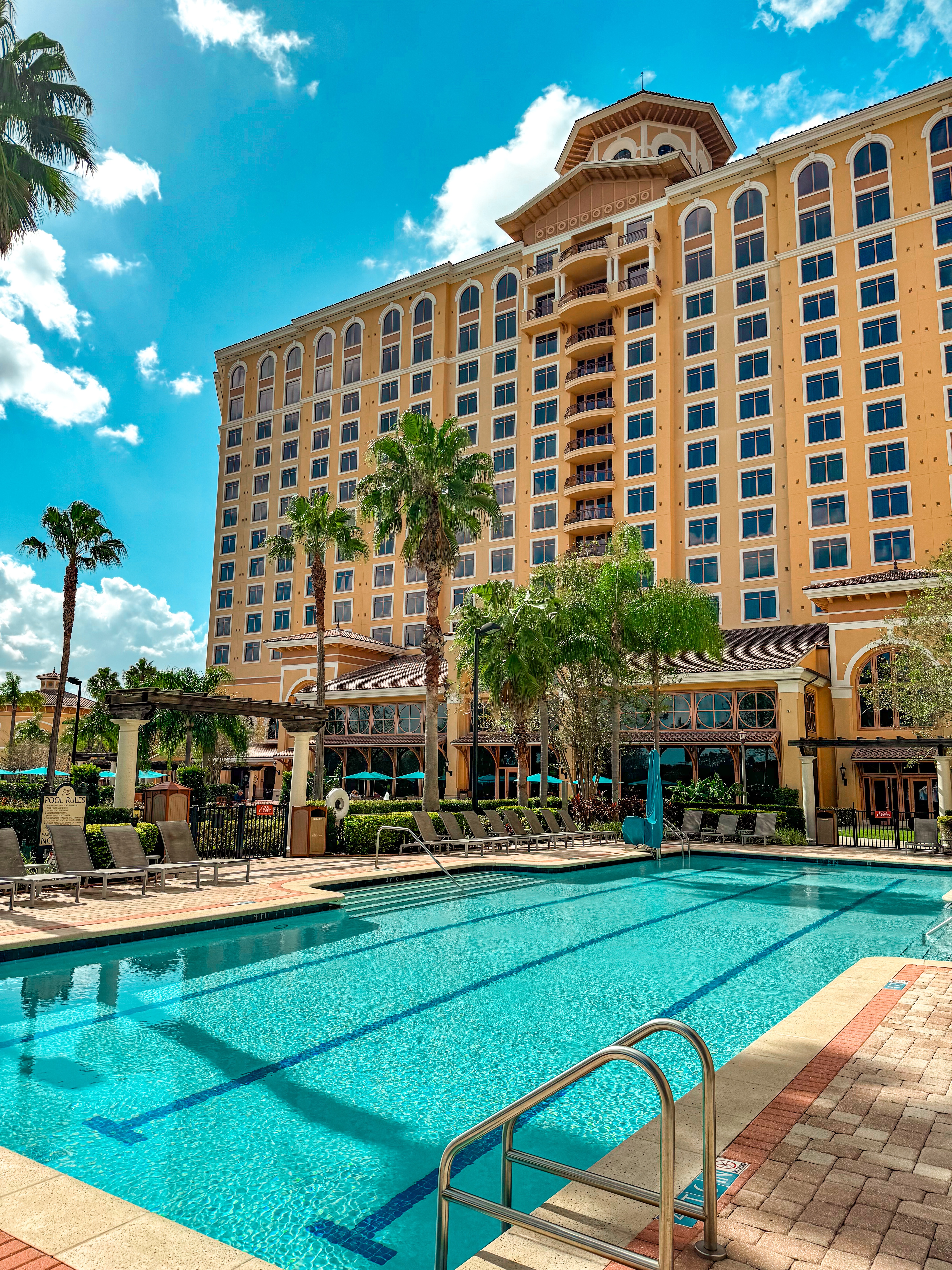 The Rosen Shingle Creek Resort with a large swimming pool, palm trees, and a bright blue sky with fluffy white clouds.