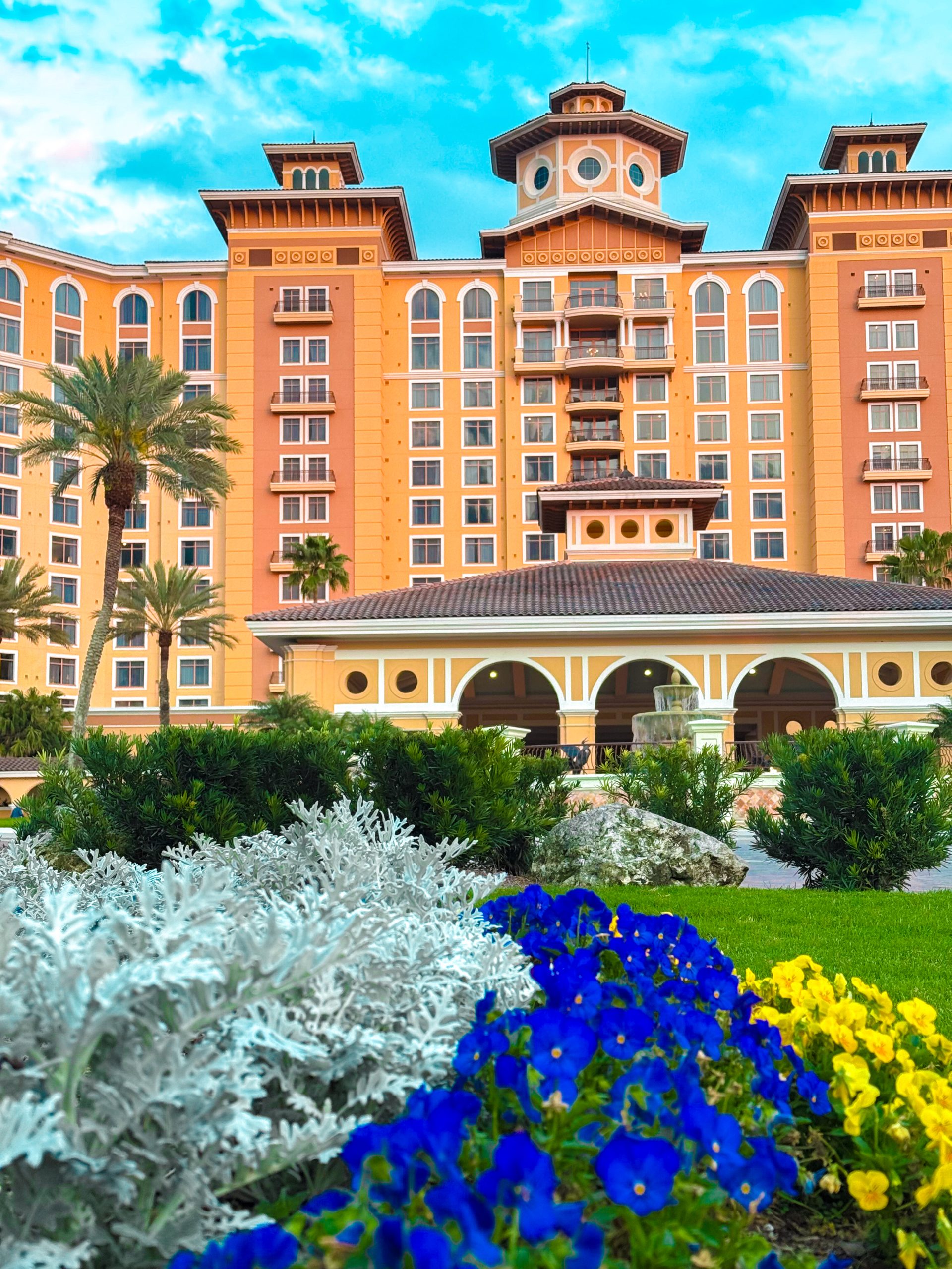 A Perfect Spa Day at Rosen Shingle Creek: What to Expect 2 The exterior front entrance of Rosen Shingle Creek with blossom flowers and palm trees.