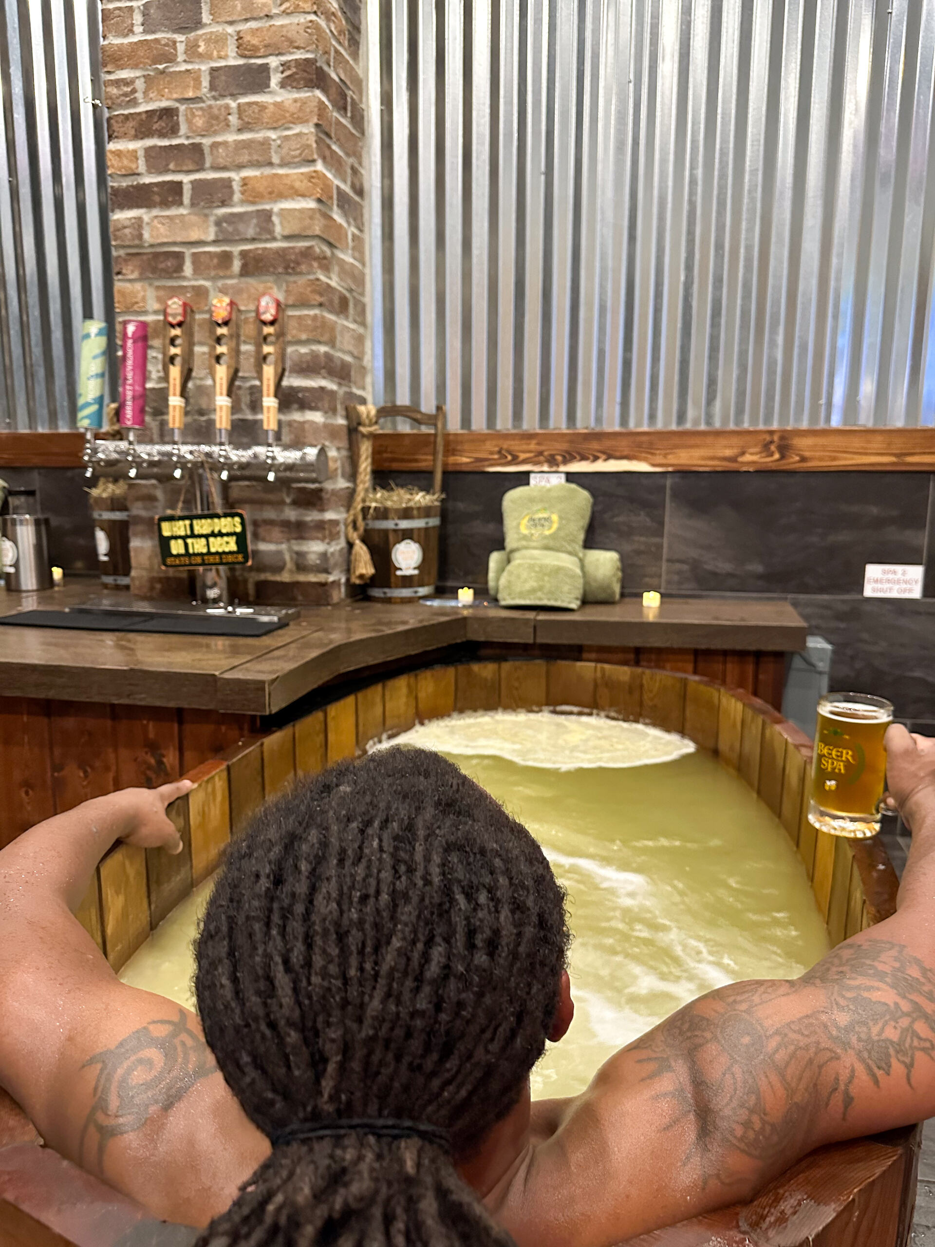 Celebrate Dad: 7 Thoughtful Father’s Day Gift Ideas 5 A man sits in a wooden beer spa tub facing away from the camera, a beer tap on a counter along the opposite wall.