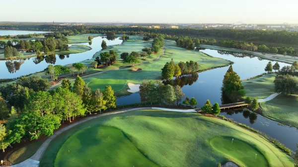 An aerial shot of rolling green golf course hills dotted with lakes and green trees. 