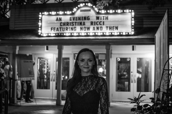 A black and white photo of a woman standing in front of a brightly lit theatre marquis at the Florida Film Festival.