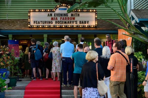 A line of people standing outside the marquis of Enzian Theatre.