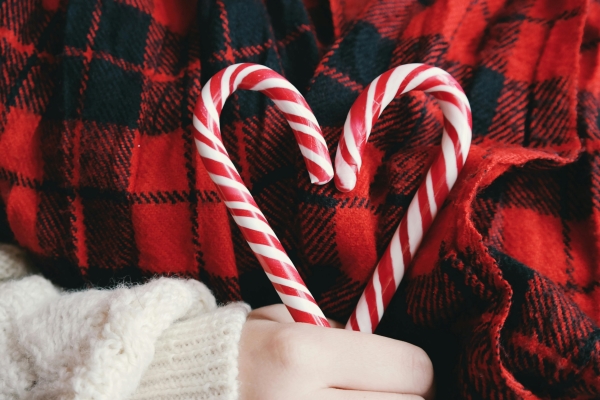 A hand holding two candy canes together to form the shape of a heart.