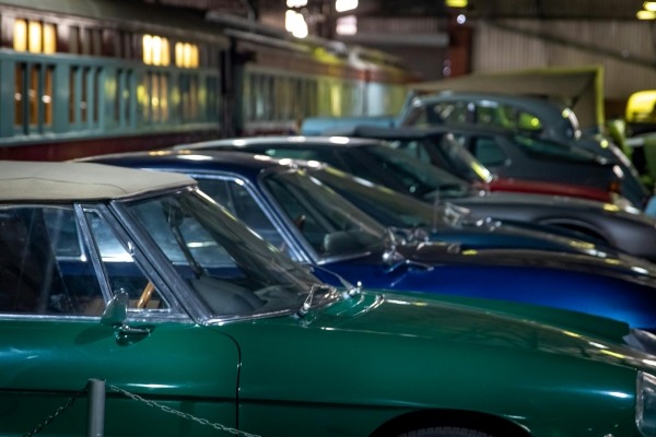A close-up on a row of vintage cars in an indoor exhibit. 