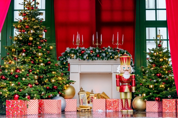 An onstage set with Christmas trees, a fireplace, wrapped gifts, and a nutcracker.