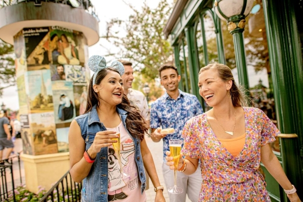 Helpful Tips & Planning Advice for EPCOT's International Food & Wine Festival 2 Two men and two women walk with Champagne flutes through France in EPCOT during the Food and Wine festival.