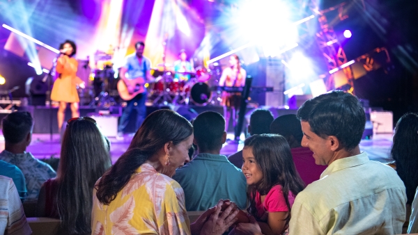 Helpful Tips & Planning Advice for EPCOT's International Food & Wine Festival 7 A mom, dad, and young daughter sit in the audience of a concert from the Eat to the Beat concert series at EPCOT.