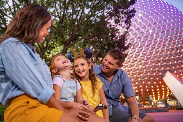 Helpful Tips & Planning Advice for EPCOT's International Food & Wine Festival 8 A mom, dad, and two daughters sit in front of a tree and Spaceship Earth at EPCOT.