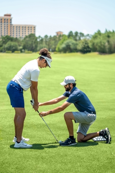 Chris Spalla assisting a player during a golf lesson at Rosen Shingle Creek resort in Orlando.