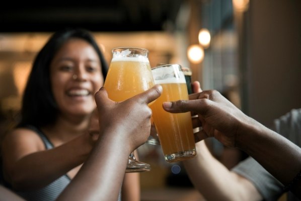 A group of people toast glasses of beer during Happy Hour. 