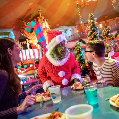 The Grinch visiting the table of two diners at Universal during the holidays. 