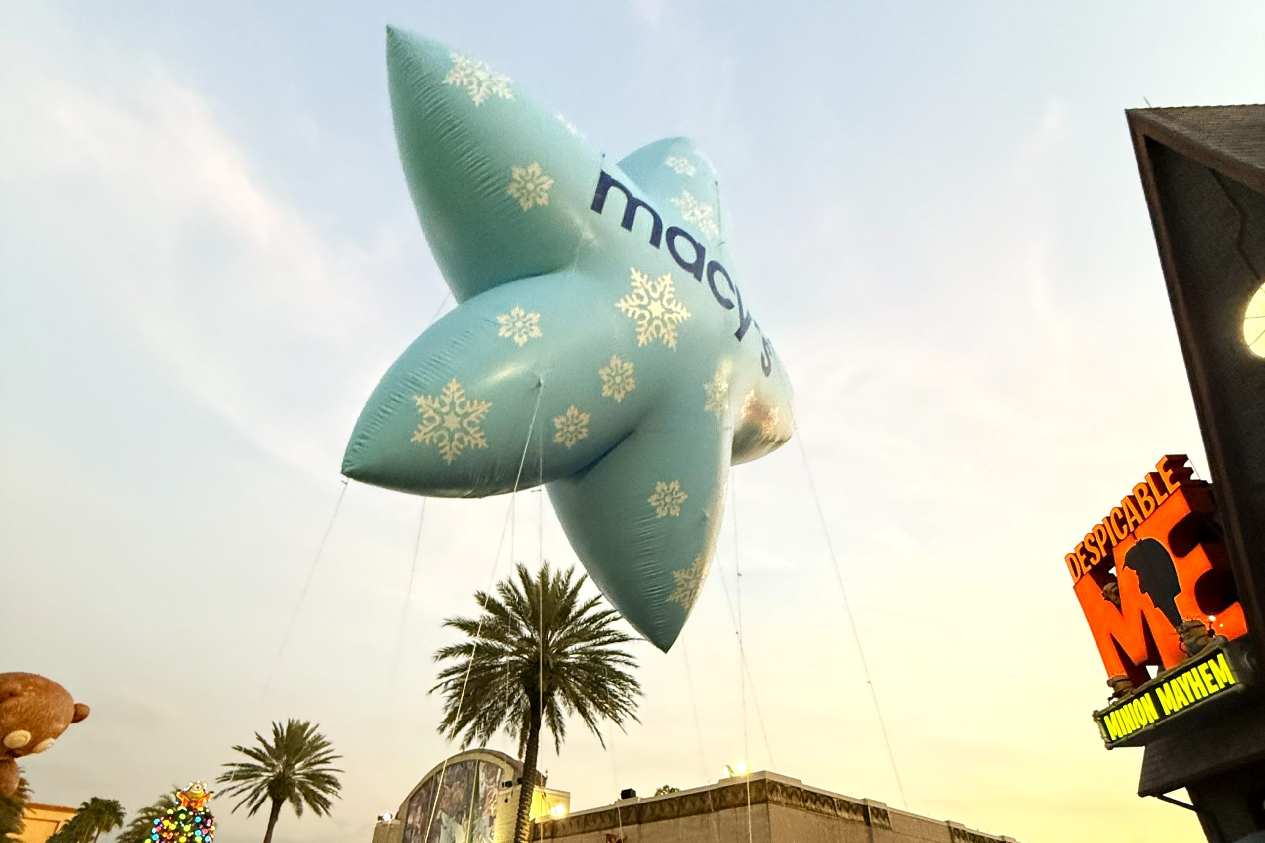 The Ultimate Guide to Orlando Holiday Events 5 A light blue star with snowflakes and the Macy's logo floats in the twilight sky at Universal Orlando's holiday parade.