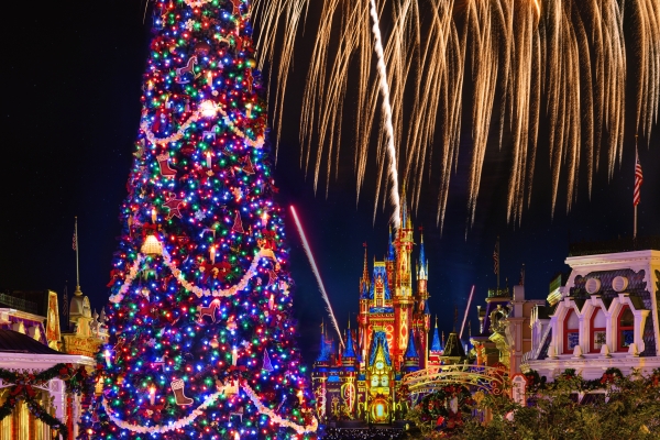 The Ultimate Guide to Orlando Holiday Events 3 A brightly lit Christmas tree at night with Cinderella Castle and fireworks in the background during Mickey's Very Merry Christmas Party, a Disney holiday event in Orlando.