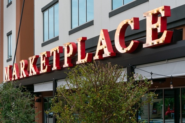 Eats for Everyone: 6 Must-Try Food Halls in Orlando 2 A large outdoor sign reads Marketplace in red letters on the front of a building.