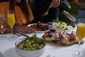Rosen Shingle Creek Mother's Day table setting with salad, small desserts, orange juice, and a beef dish before a woman in an orange dress.