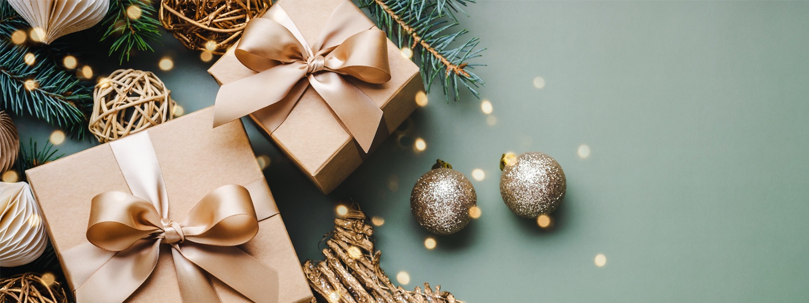 A green background with gold ornaments, pine branches, and brown and gold wrapped presents