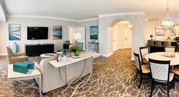 A suite with a sofa and armchairs, a dining table, and a bar