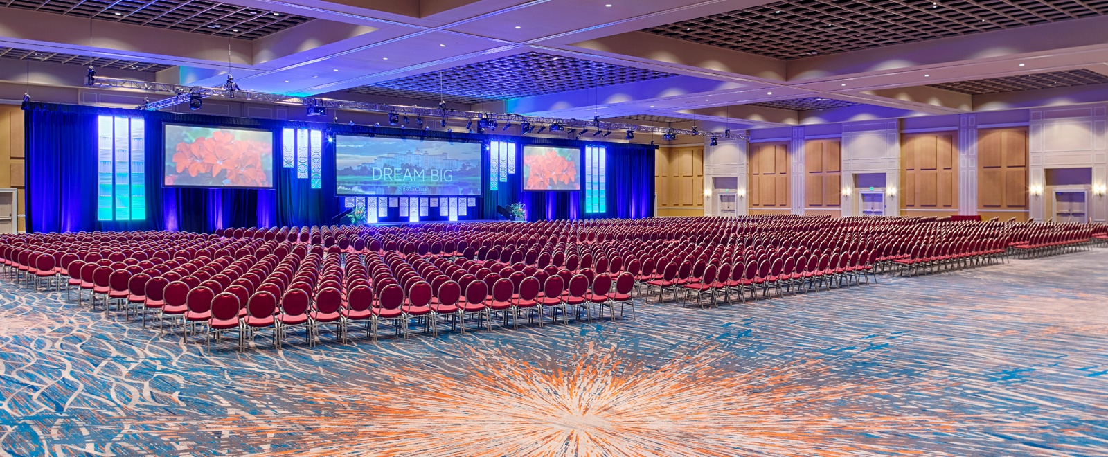 A massive ballroom set with hundreds of red chairs for a large presentation