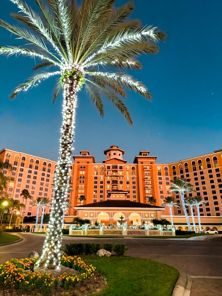 A festive palm tree adorned with Christmas lights in front of Rosen Shingle Creek in Orlando, the perfect romantic holiday getaway.