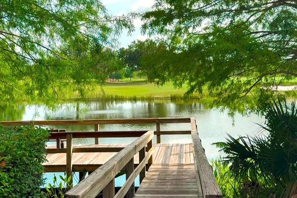 The corner of a dock at Rosen Shingle Creek overlooking a beautiful lake and surrounded by green tree branches.