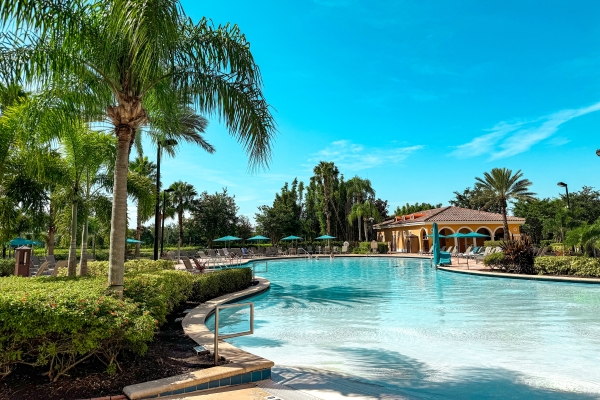 A curving, crystal clear blue pool surrounded by blue umbrellas and palm trees, the perfect setting for a digital detox at Rosen Shingle Creek.