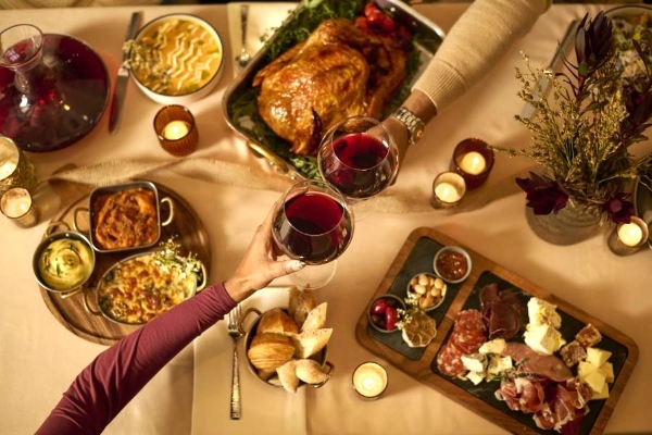 Thanksgiving Without Cooking: Rosen Shingle Creek is a Holiday Escape 2 An overhead shot of two arms toasting wine glasses over a beautiful spread of food while celebrating Thanksgiving at Rosen Shingle Creek.