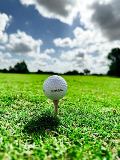 A close-up of a golf ball on a tee looking up at a cloudy blue sky on the Rosen Shingle Creek golf course.