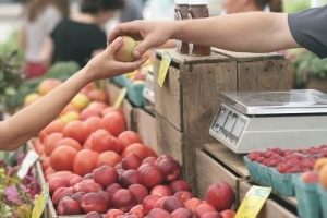 Cashier handing customer apples at a farmers market