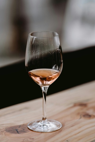 A glass of pale pink wine on a wooden table.
