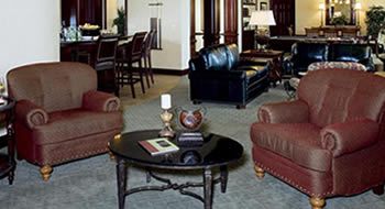 Two large brown armchairs and a coffee table with large brown leather sofas in the background