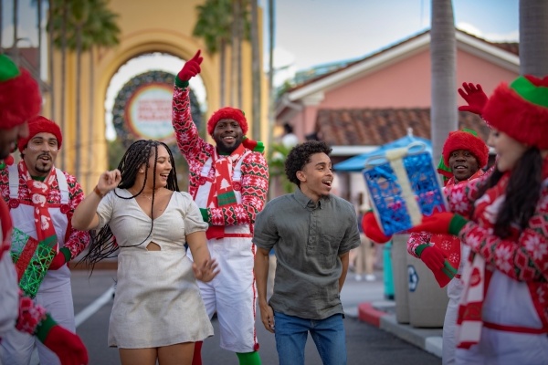 Visitors and performers dancing in the streets during a Universal Christmas parade. 
