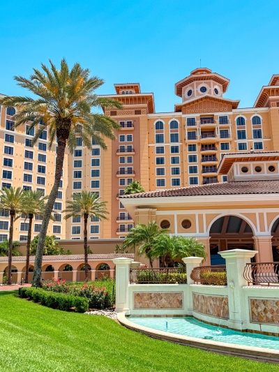 A close-up of the front entrance of Rosen Shingle Creek, with palm trees, beautiful landscaping, and a fountain.