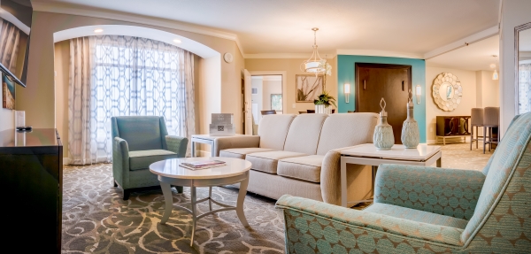 A comfortable suite with a sofa, two chairs, and a large arched window. 