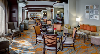 A large suite with tables and chairs, sofas, and wood beams on the ceiling